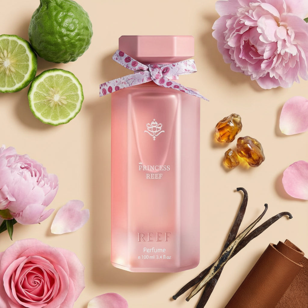 Pink bottle labeled 'Princess Reef' surrounded by flowers, limes, and vanilla beans on a white background
